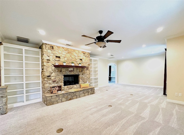 unfurnished living room featuring ceiling fan, a stone fireplace, light colored carpet, and ornamental molding