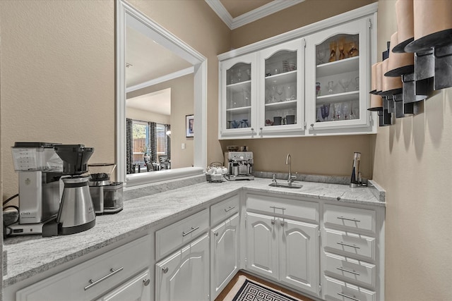 kitchen featuring white cabinetry, sink, crown molding, and light stone countertops