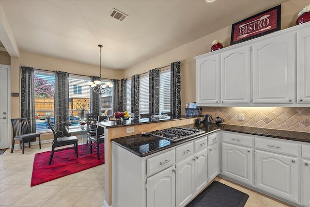 kitchen with white cabinetry, decorative light fixtures, and stainless steel gas stovetop