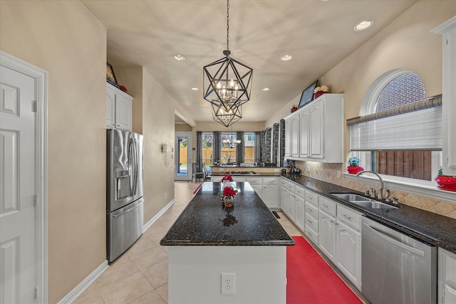 kitchen featuring sink, appliances with stainless steel finishes, a kitchen island, a notable chandelier, and white cabinets