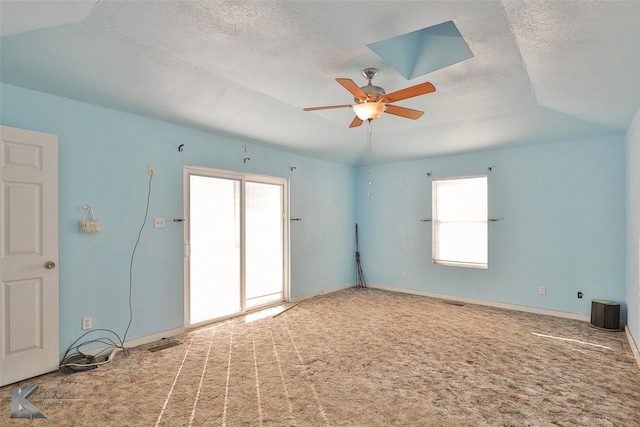 spare room featuring a textured ceiling, carpet floors, ceiling fan, and vaulted ceiling with skylight