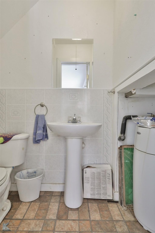 bathroom featuring toilet and tile walls