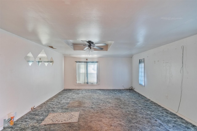 empty room featuring ceiling fan, a raised ceiling, and carpet floors