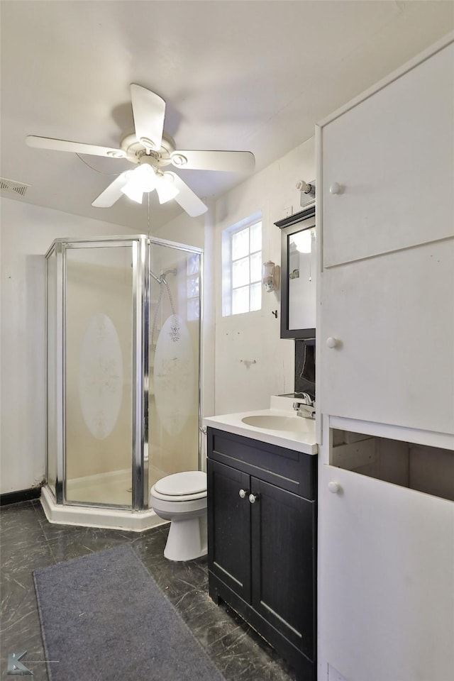 bathroom with vanity, toilet, ceiling fan, and a shower with shower door