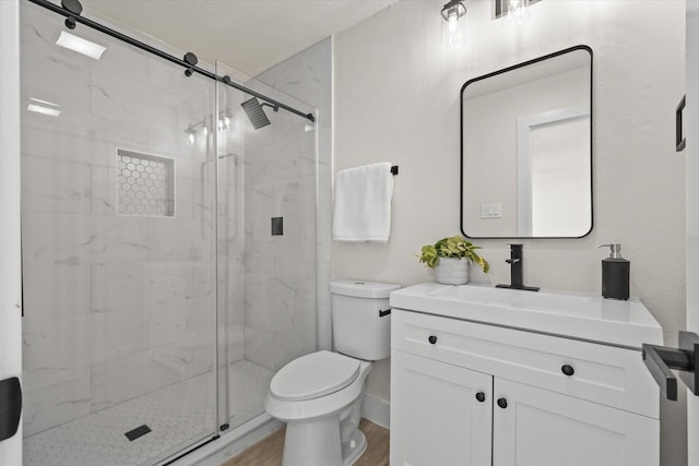 bathroom with hardwood / wood-style floors, vanity, toilet, and a shower with shower door