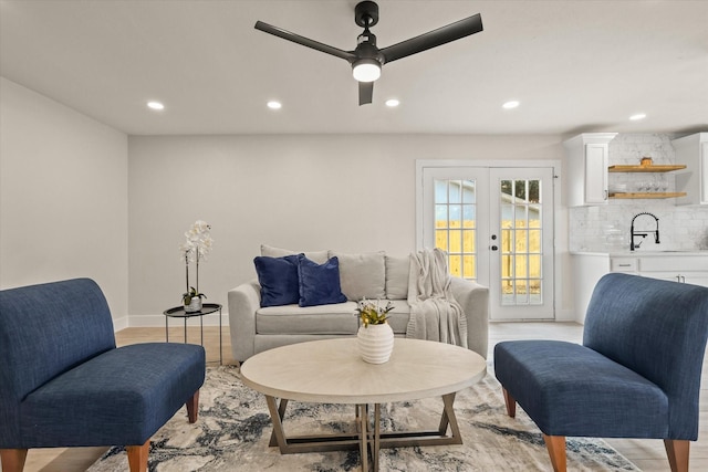 living room with french doors, light hardwood / wood-style floors, ceiling fan, and sink