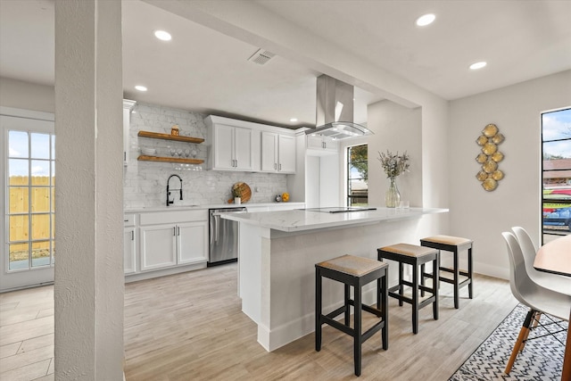 kitchen featuring white cabinetry, island range hood, dishwasher, and light hardwood / wood-style floors