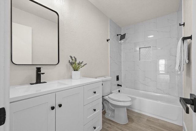 full bathroom with hardwood / wood-style floors, vanity, tiled shower / bath combo, and toilet