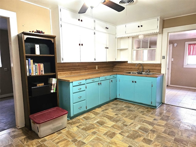 kitchen with ceiling fan, sink, white cabinets, and butcher block countertops