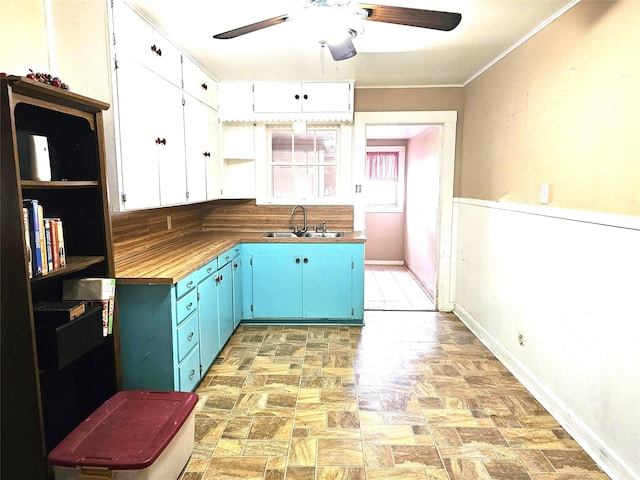 kitchen featuring sink, wooden counters, ceiling fan, ornamental molding, and white cabinets