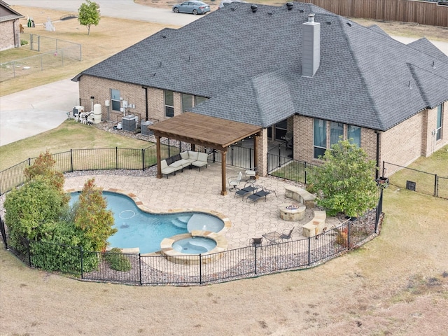 exterior space featuring a pool with connected hot tub, a fenced backyard, a yard, a fire pit, and a patio area