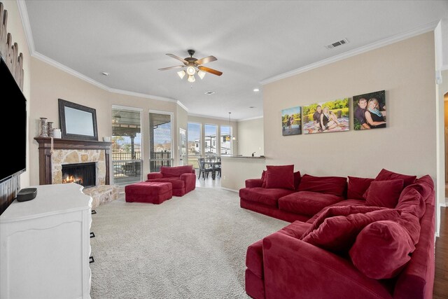 living room with crown molding, ceiling fan, and a fireplace