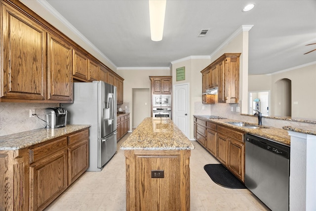 kitchen with a kitchen island, sink, stainless steel appliances, crown molding, and light stone countertops