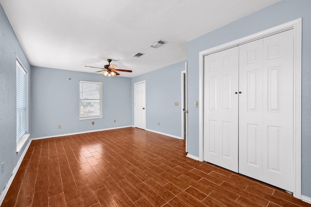 unfurnished bedroom with ceiling fan, dark hardwood / wood-style flooring, and two closets