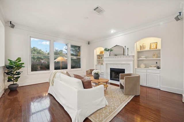 living room with dark hardwood / wood-style floors, crown molding, a fireplace, and built in shelves