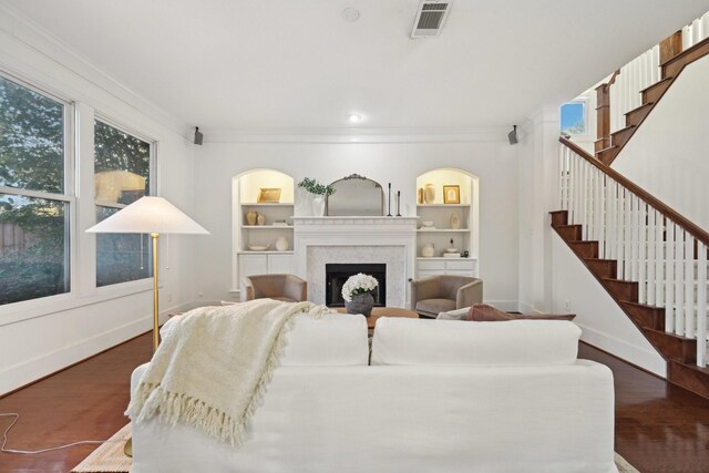 living room featuring built in shelves, crown molding, and dark wood-type flooring