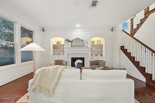 living room featuring dark hardwood / wood-style flooring, built in shelves, and ornamental molding