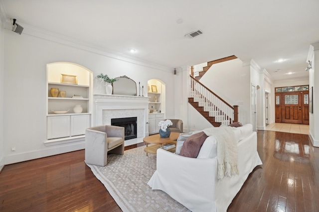 living room featuring crown molding, built in features, and hardwood / wood-style flooring