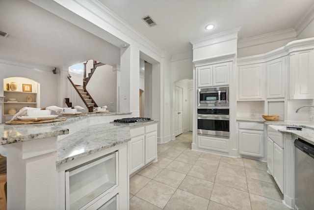 kitchen featuring sink, light tile patterned floors, appliances with stainless steel finishes, white cabinets, and ornamental molding