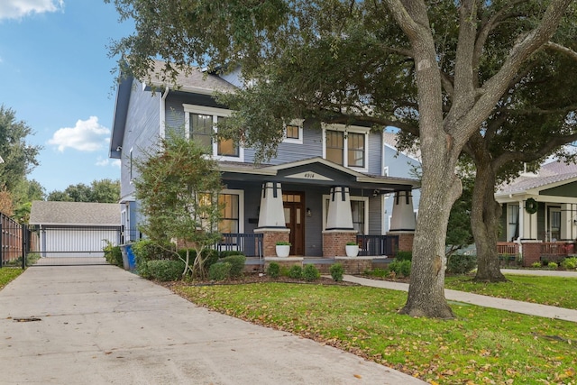 view of front of home with a front lawn, covered porch, an outdoor structure, and a garage