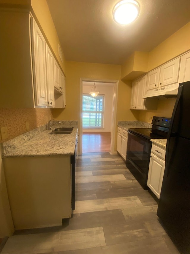 kitchen with black appliances, sink, light hardwood / wood-style flooring, light stone countertops, and white cabinetry