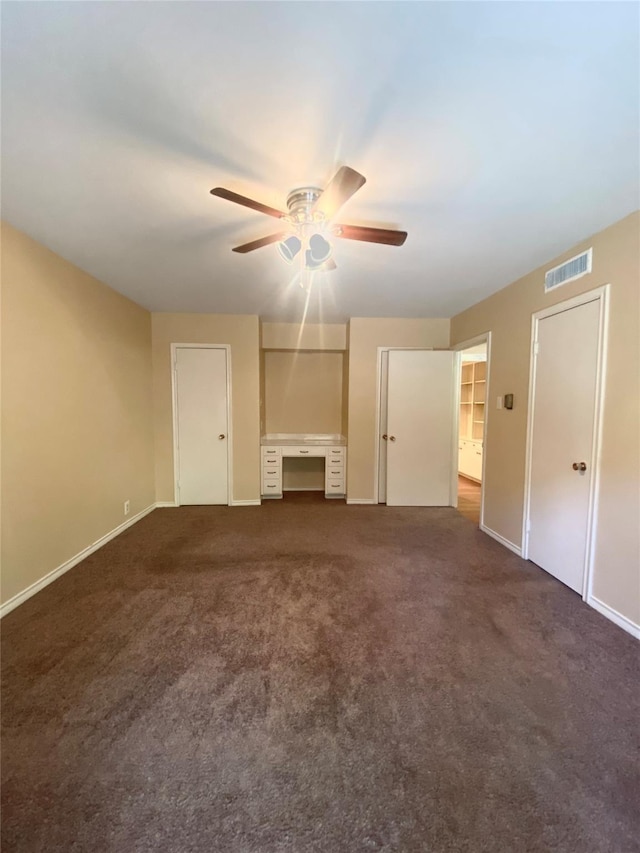 unfurnished living room with ceiling fan and dark colored carpet