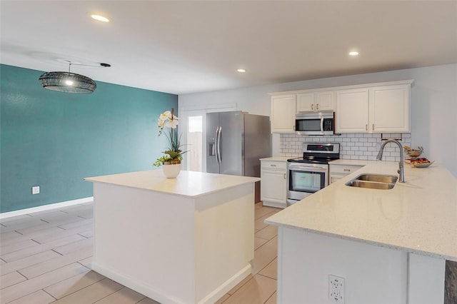 kitchen featuring kitchen peninsula, appliances with stainless steel finishes, backsplash, sink, and white cabinetry