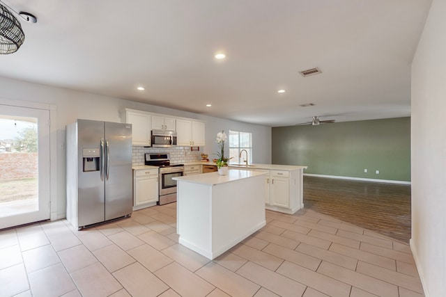 kitchen featuring white cabinets, a center island, sink, and appliances with stainless steel finishes