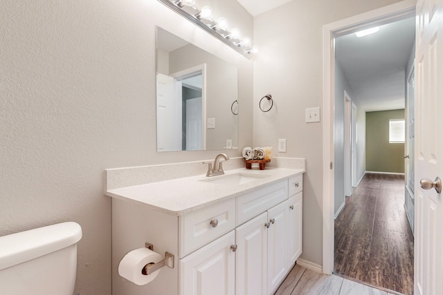 bathroom with toilet, vanity, and hardwood / wood-style flooring