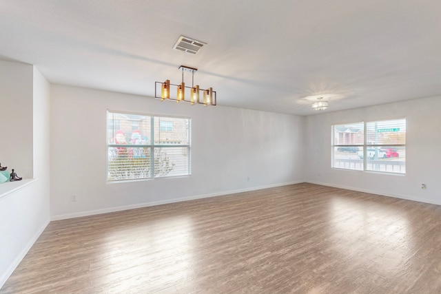 unfurnished room with light wood-type flooring and an inviting chandelier