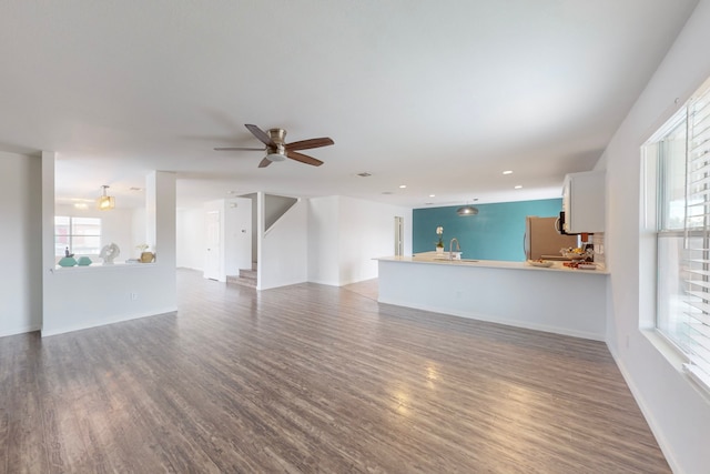 unfurnished living room featuring ceiling fan, sink, and wood-type flooring