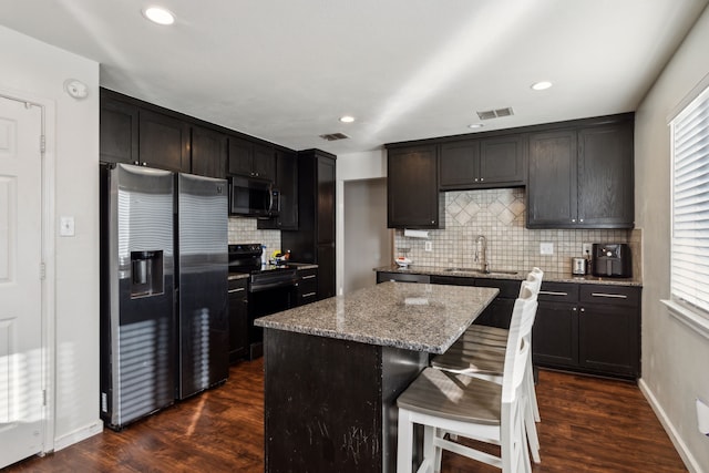 kitchen with a kitchen island, appliances with stainless steel finishes, sink, dark hardwood / wood-style flooring, and light stone countertops