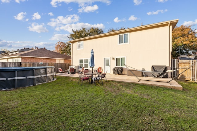 back of property with a fenced in pool, a patio, and a lawn