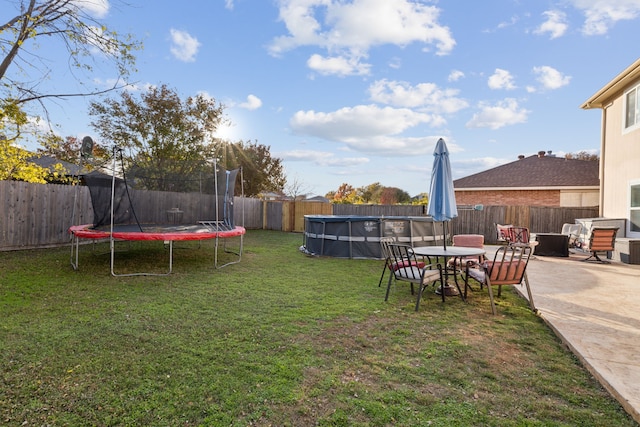 view of yard featuring a patio, a covered pool, and a trampoline