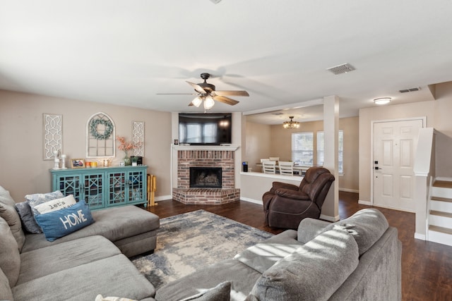 living room featuring ceiling fan with notable chandelier, dark hardwood / wood-style flooring, and a fireplace