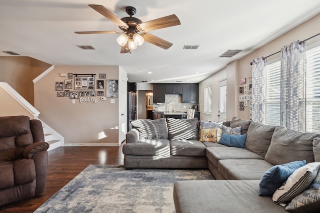 living room featuring dark wood-type flooring and ceiling fan