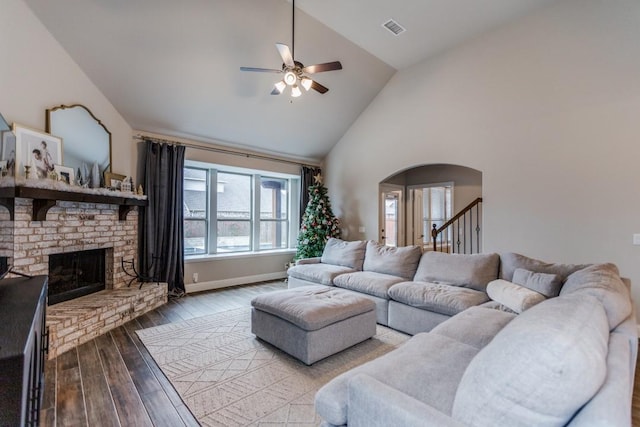 living room featuring ceiling fan, a fireplace, high vaulted ceiling, and light hardwood / wood-style floors