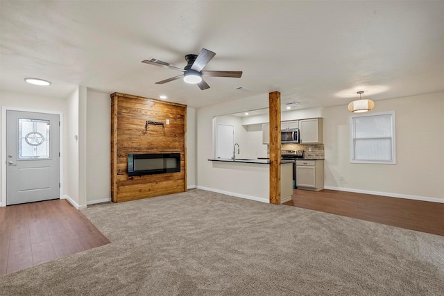 unfurnished living room with ceiling fan, a fireplace, sink, and light hardwood / wood-style flooring