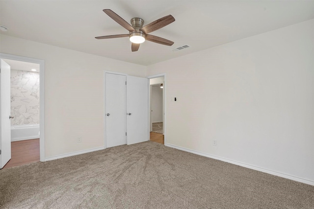 unfurnished bedroom with ceiling fan, carpet floors, and ensuite bath