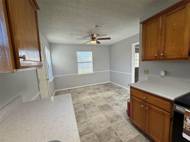 kitchen with ceiling fan, electric range oven, and a textured ceiling