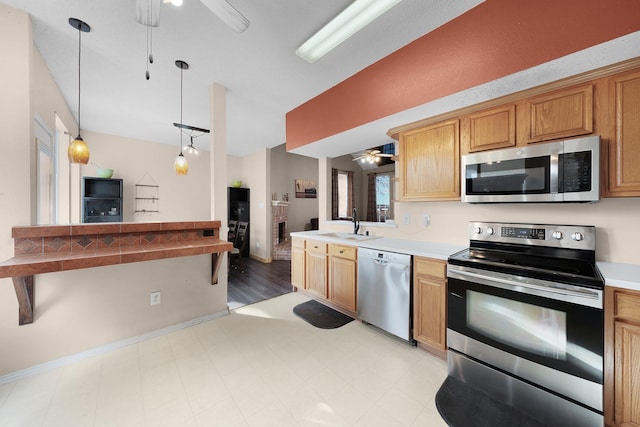 kitchen with sink, appliances with stainless steel finishes, ceiling fan, and hanging light fixtures