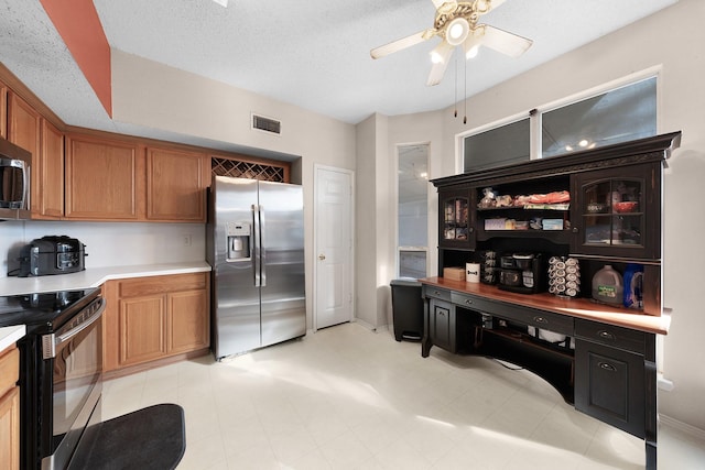 kitchen with stainless steel appliances, a textured ceiling, and ceiling fan