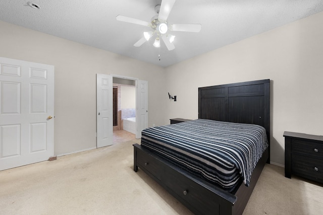 bedroom with connected bathroom, light carpet, ceiling fan, and a textured ceiling