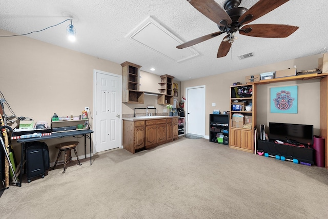 kitchen featuring a textured ceiling, light colored carpet, ceiling fan, and a kitchen bar