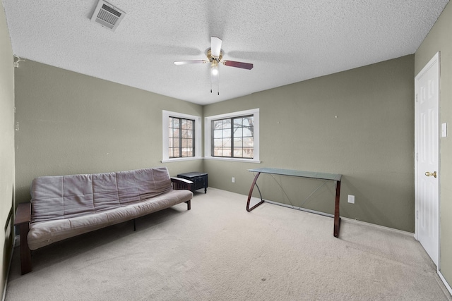 sitting room with ceiling fan, light carpet, and a textured ceiling