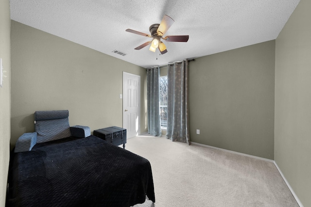 bedroom with light colored carpet, ceiling fan, and a textured ceiling