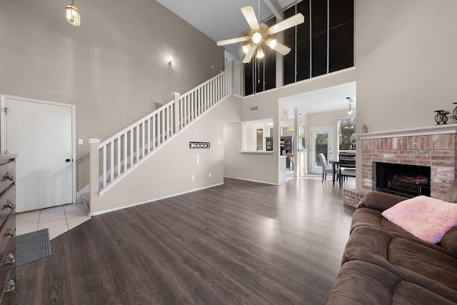 living room with a high ceiling, wood-type flooring, ceiling fan, and a fireplace