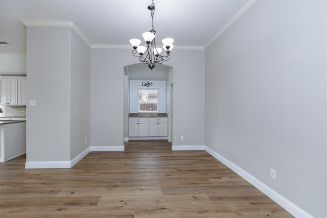 unfurnished dining area with light wood-type flooring, ornamental molding, and a chandelier