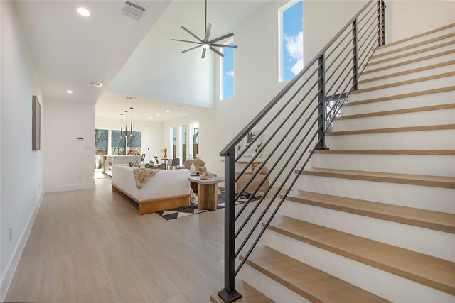 stairway with hardwood / wood-style flooring and ceiling fan