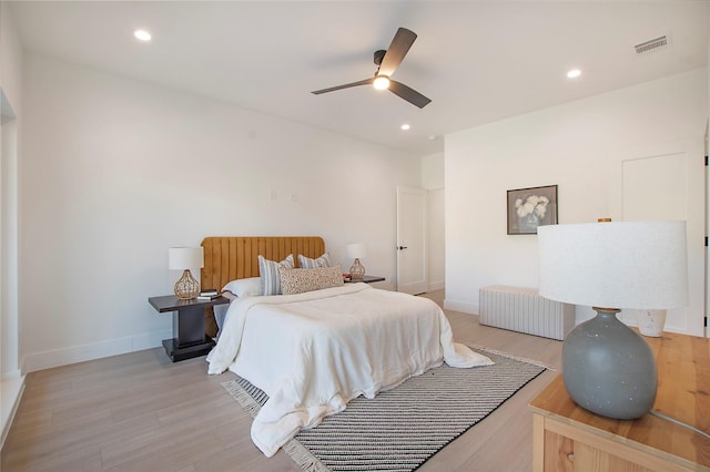 bedroom featuring ceiling fan, radiator heating unit, and light hardwood / wood-style flooring